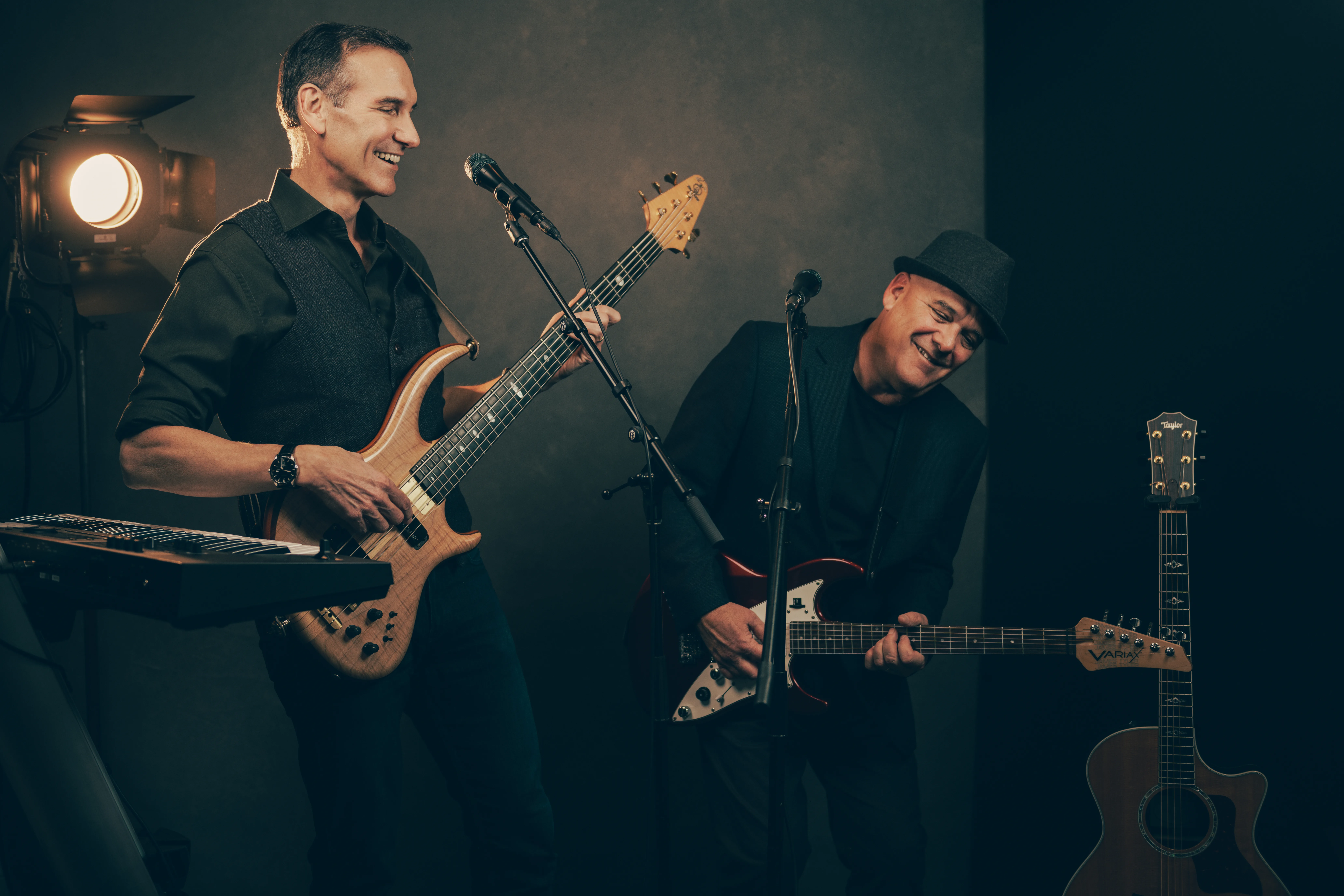 Musicians with electric guitars sharing a moment of joy, highlighted by moody lighting in a personal brand photoshoot that captures their creative essence.